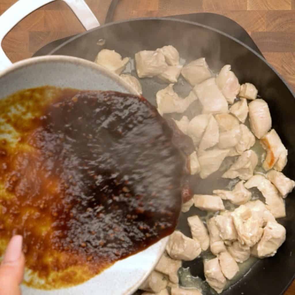keto teriyaki sauce Overhead shot of keto teriyaki saucing being poured onto cooking chicken in a frying pan.
