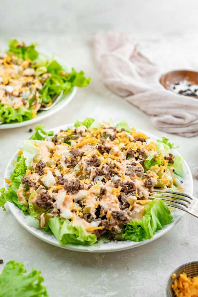 An angled shot of big mac salad in a white bowl with a fork stuck in it.