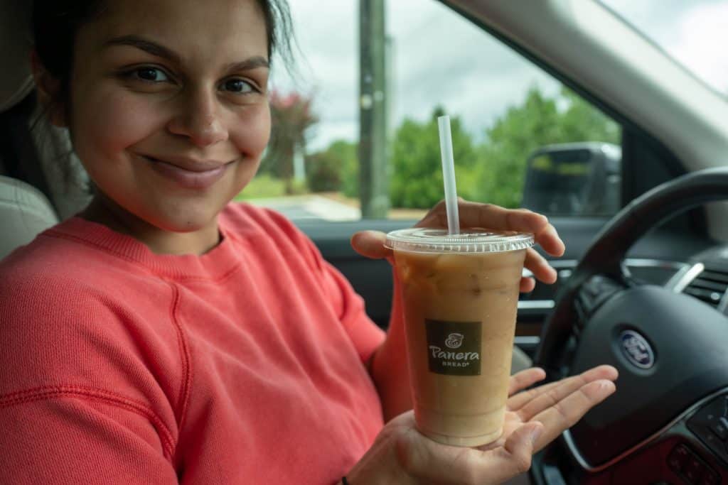 woman holding a keto panera iced coffee in the car