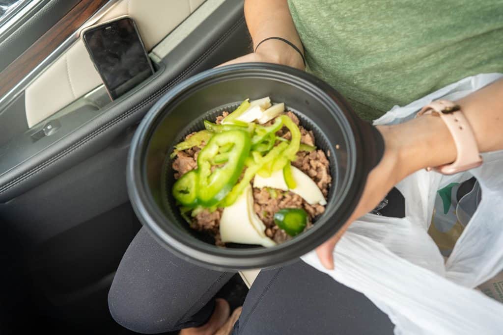 A keto subway salad bowl that is in a bowl being held in a car