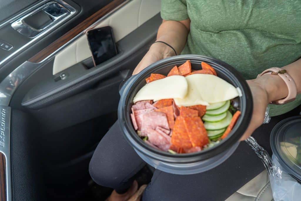 A keto subway sandwich without the bread in a bowl being held in a car