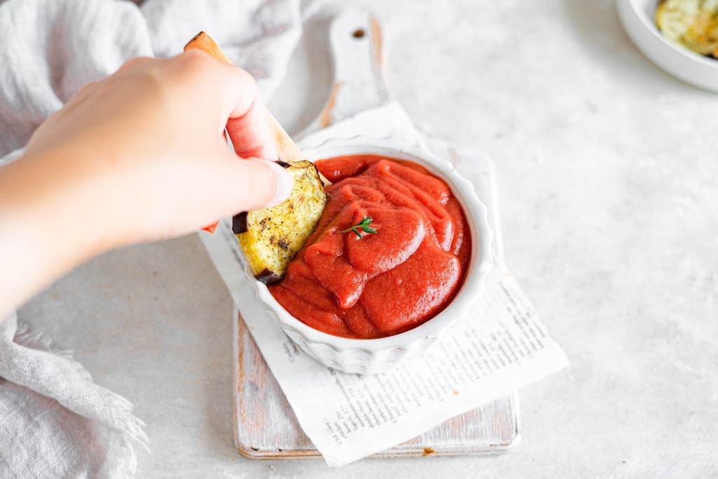 dipping a vegetable into the completed keto ketchup recipe