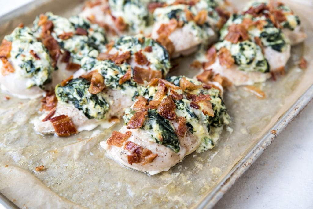chicken breasts topped with bacon on parchment paper