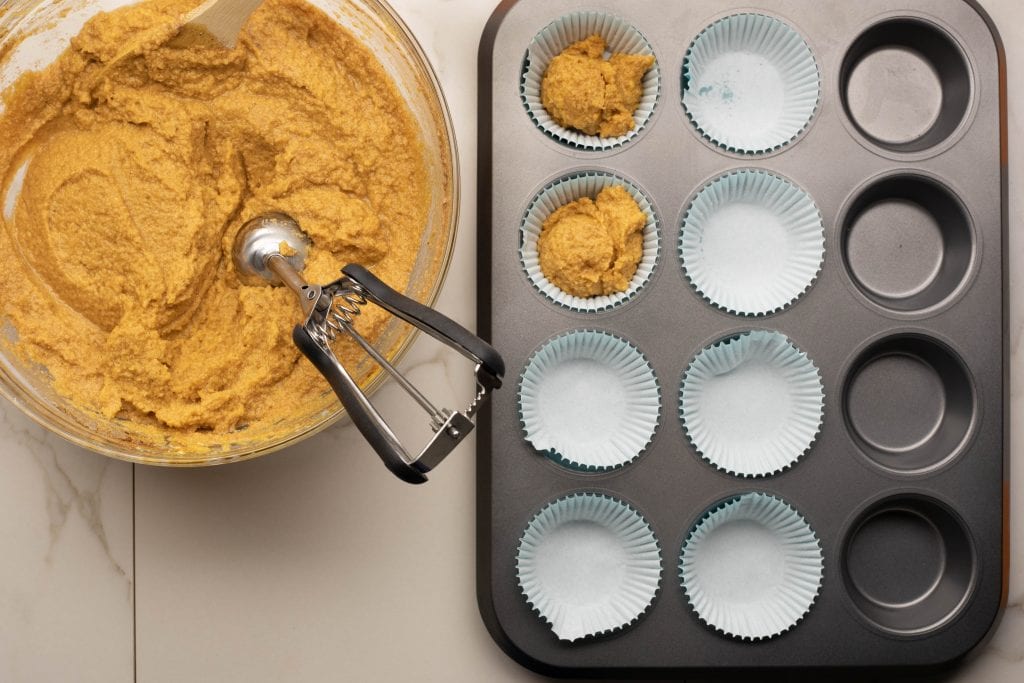 keto pumpkin muffins using a cookie scooper to put the muffin batter in the baking tins