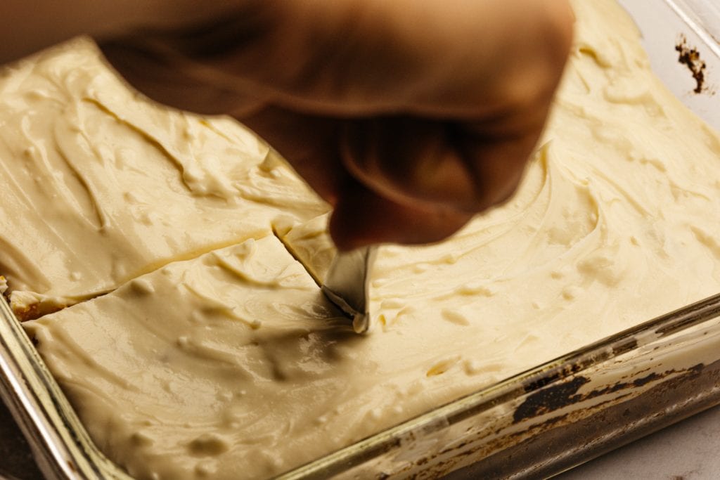 slicing into the pumpkin bars with cream cheese icing