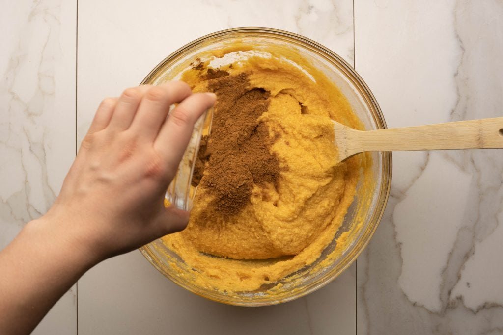 keto pumpkin muffins adding the pumpkin pie spice to the batter
