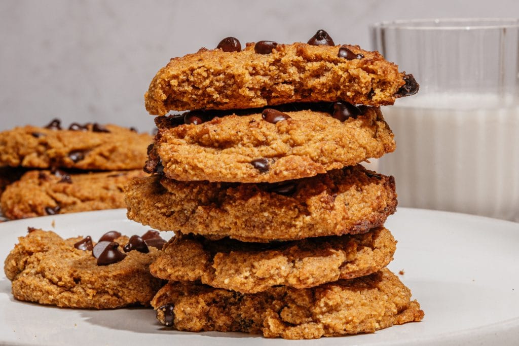 Keto Pumpkin Chocolate Chip Cookies cookies stacked on the table with a glass of milk in the background