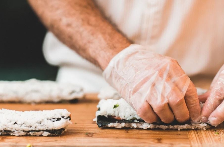 chef making a sushi roll with rice