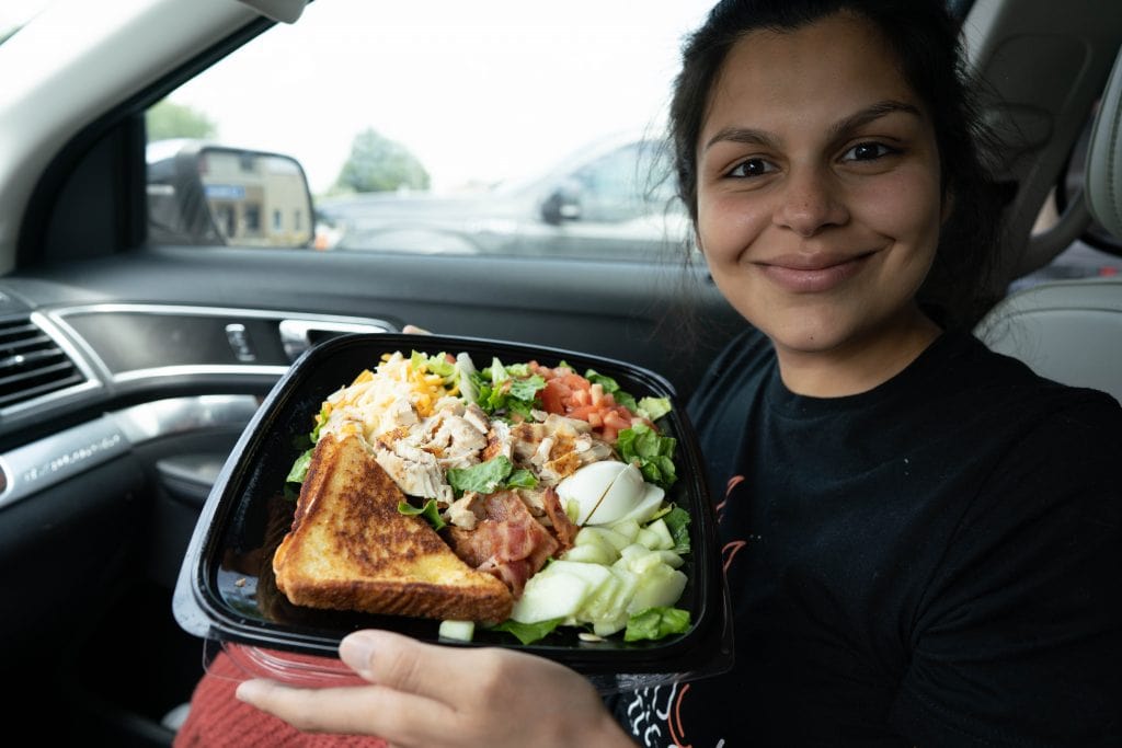 woman holding a cobb salad from zaxbys in a car