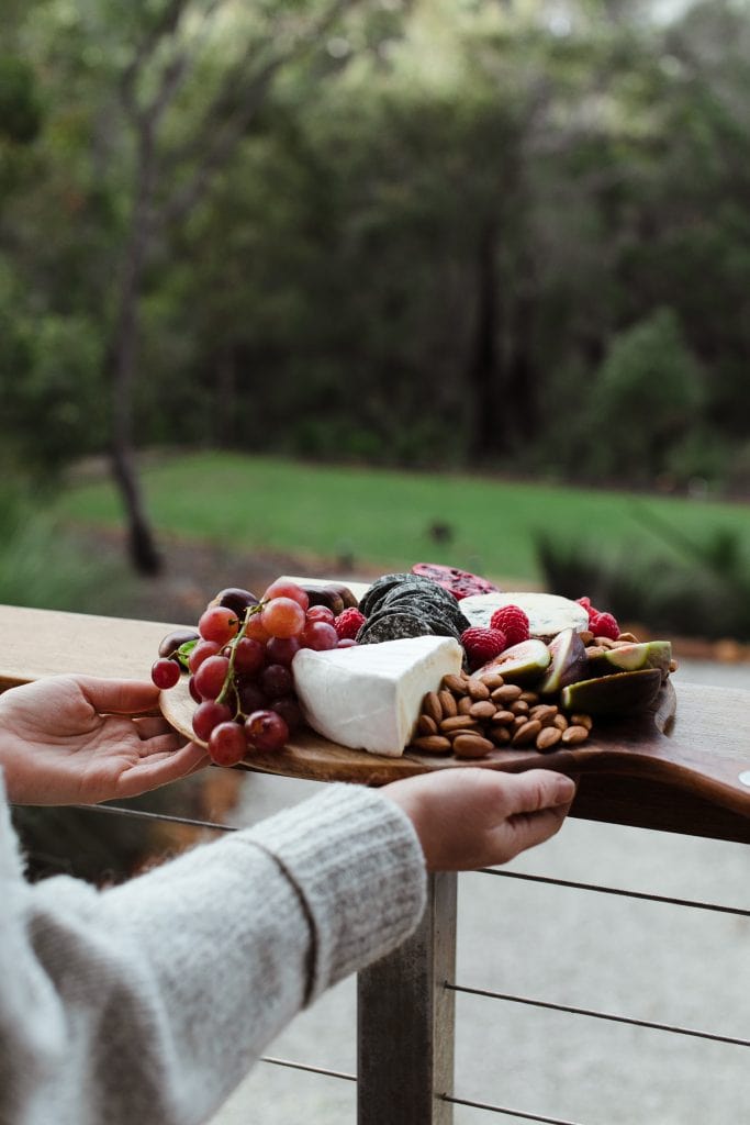 woman holding plate of meat and cheese on porch