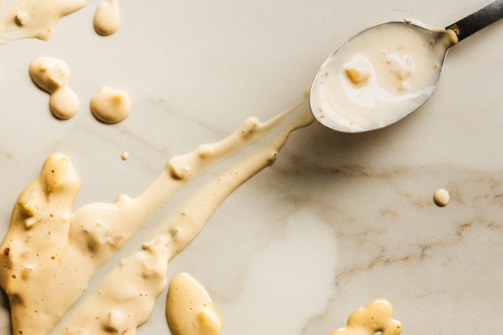 A silver spoon resting on marble with thousand island dressing. 