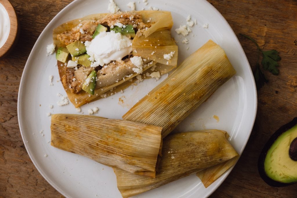 4 tamales on a plate with one opened