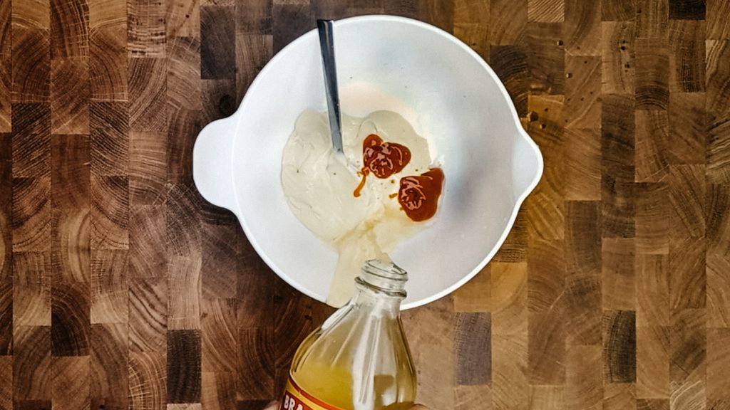 keto thousand island dressing Pouring apple cider vinegar into the mayo