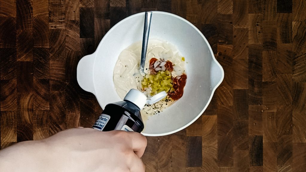 keto thousand island dressing Adding stevia into a bowl of thousand island dressing ingredients