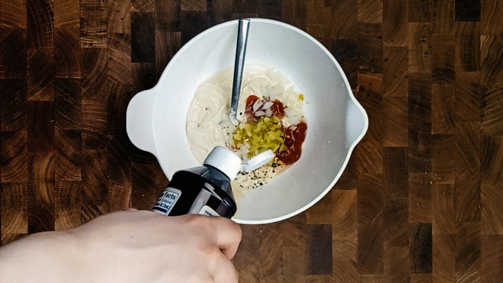 Adding stevia into a bowl of thousand island dressing ingredients