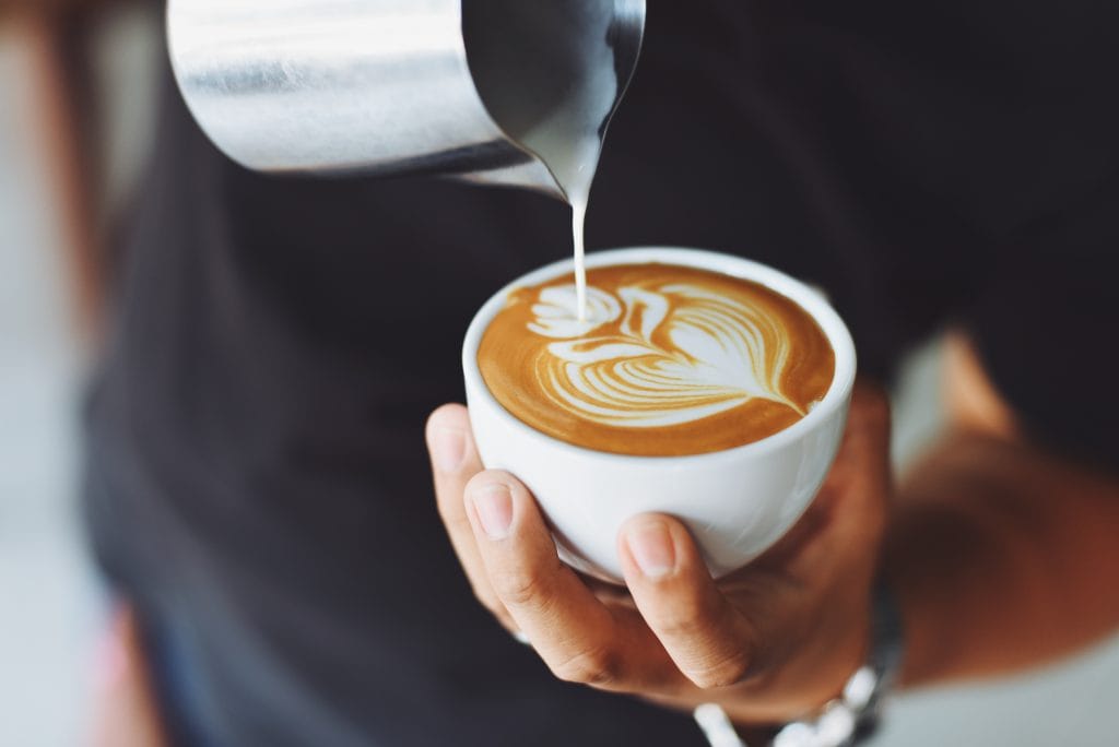 barista pouring half and half into a cup of coffee