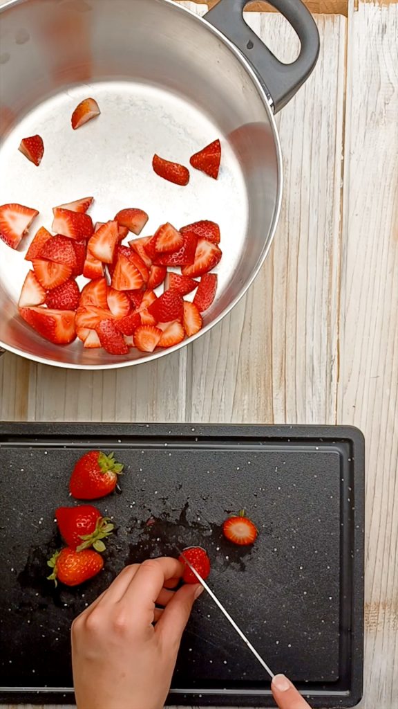 chopping strawberries on a cutting board