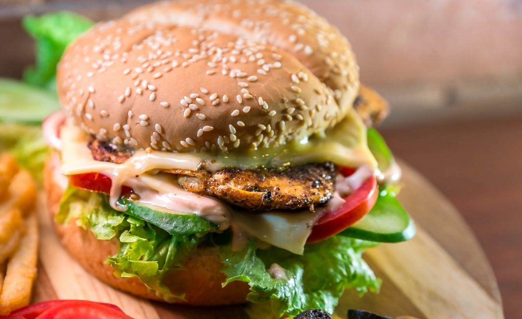A grilled chicken breast on a sesame seed bun and bed of lettuce. 