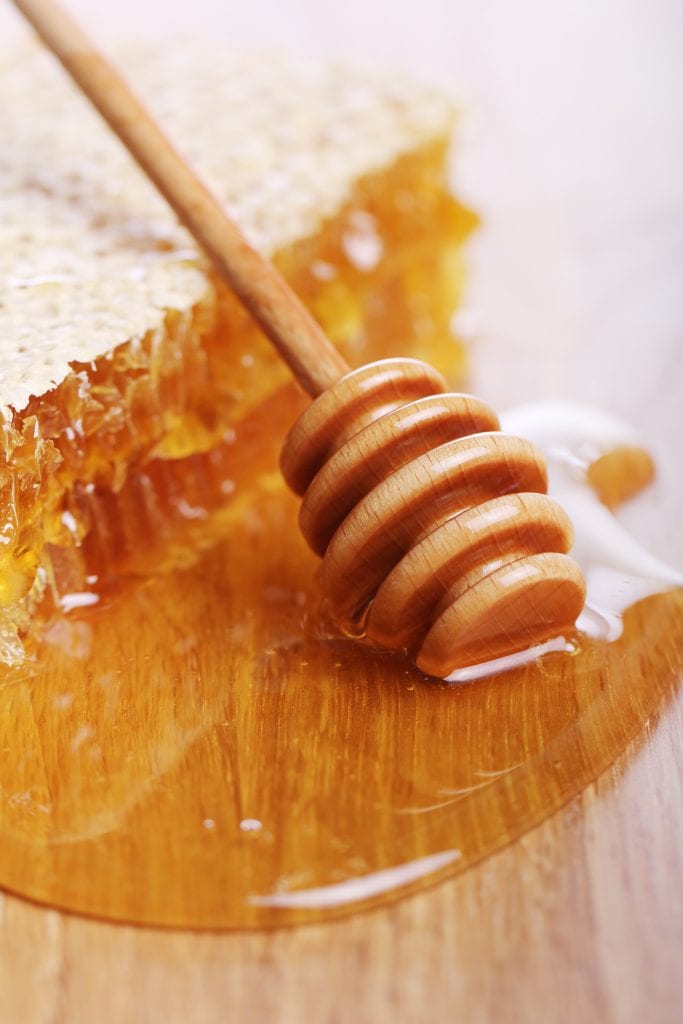 A wooden table with lots of honey spilled on it. 