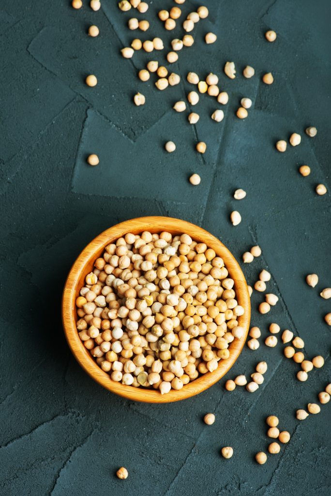 raw chickpea in a wooden bowl and on a table