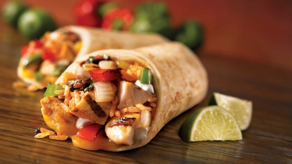 tortilla wraps with chicken meat and vegetables on wooden table close up