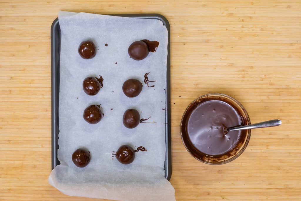 peanut butter balls coated with chocolate on the baking sheet