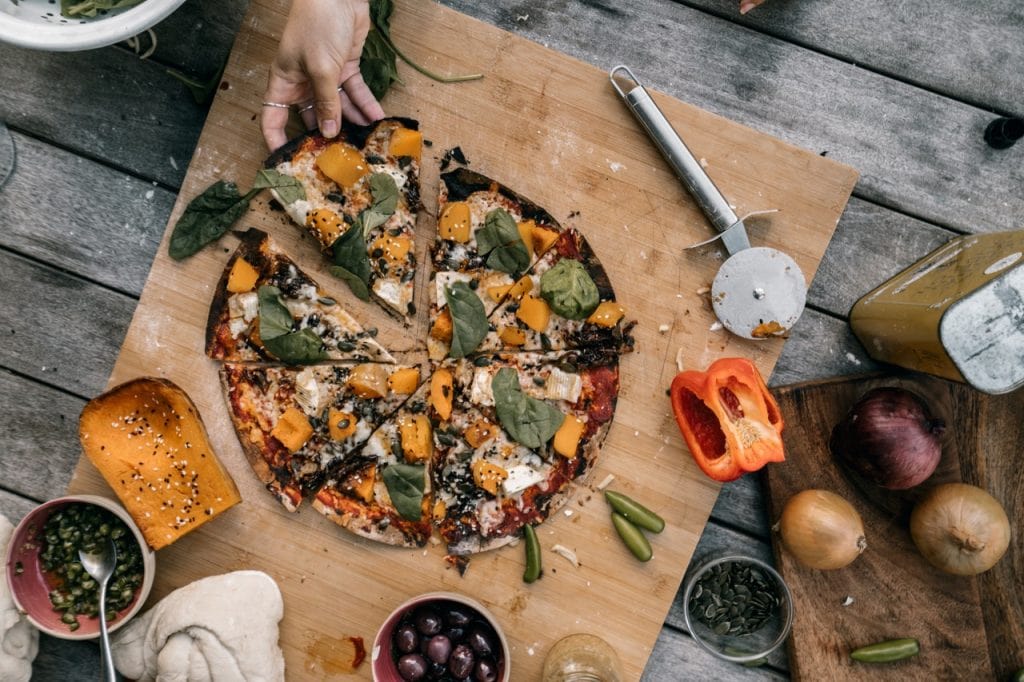 woman's hand taking keto pizza slice from wooden board