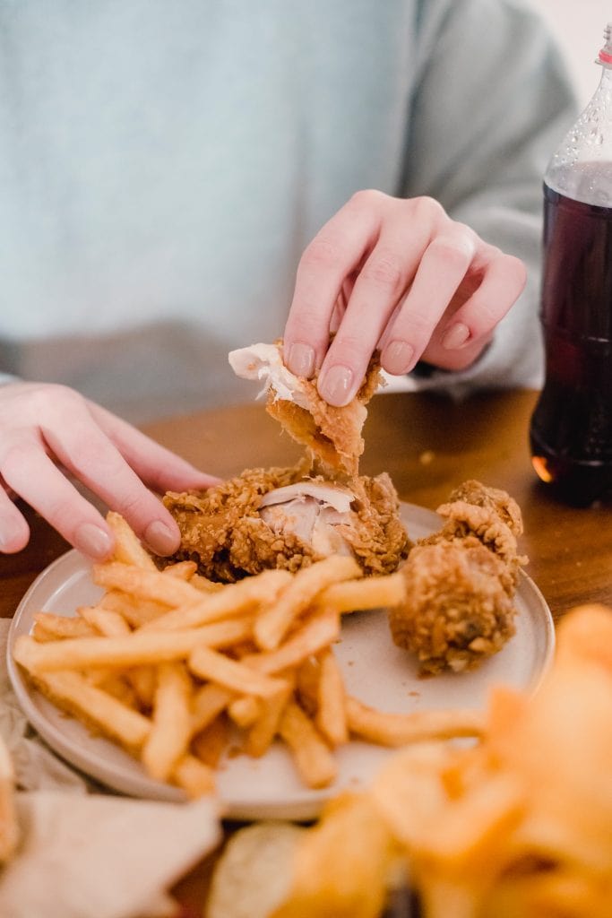 woman having snack with fries and chicken wings