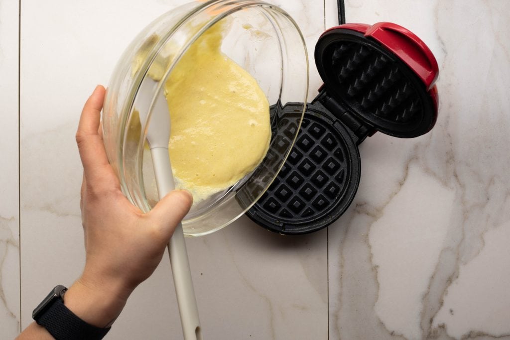 wonder bread chaffle poring chaffle batter into mini waffle maker