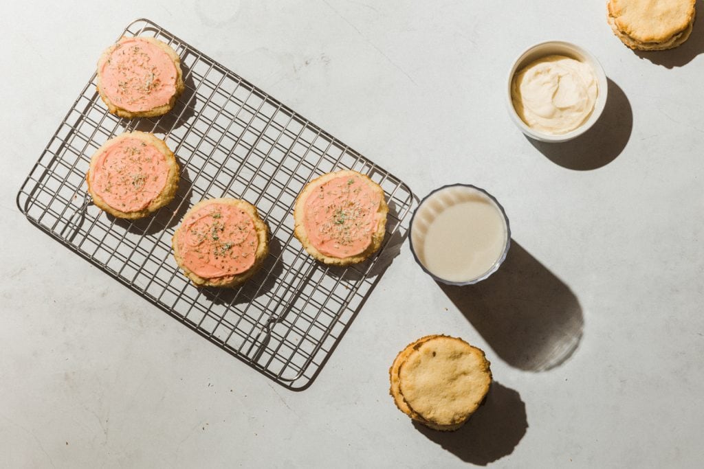 sugar cookies on the oven rack with flosting and a glass of milk