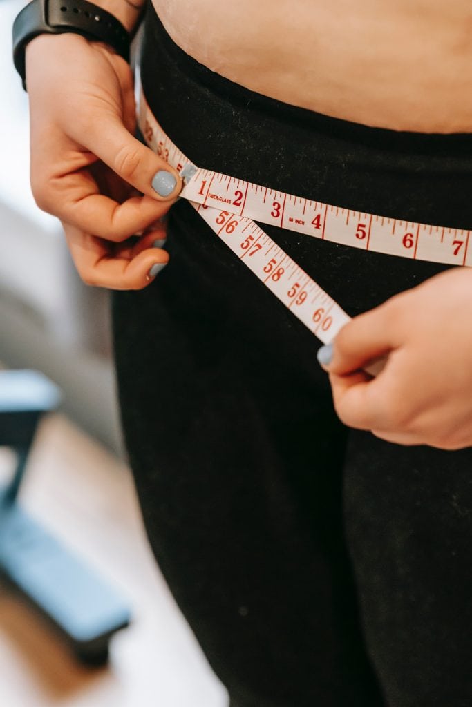 women measuring her hips with measuring tape