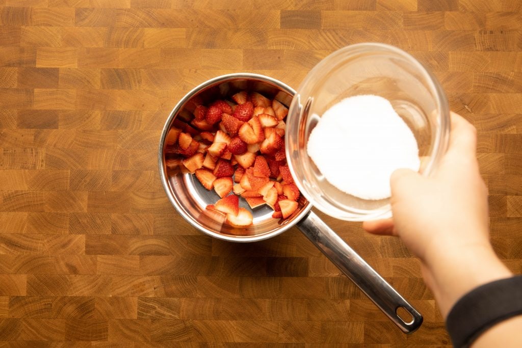 adding sweetener to the pot with strawberries