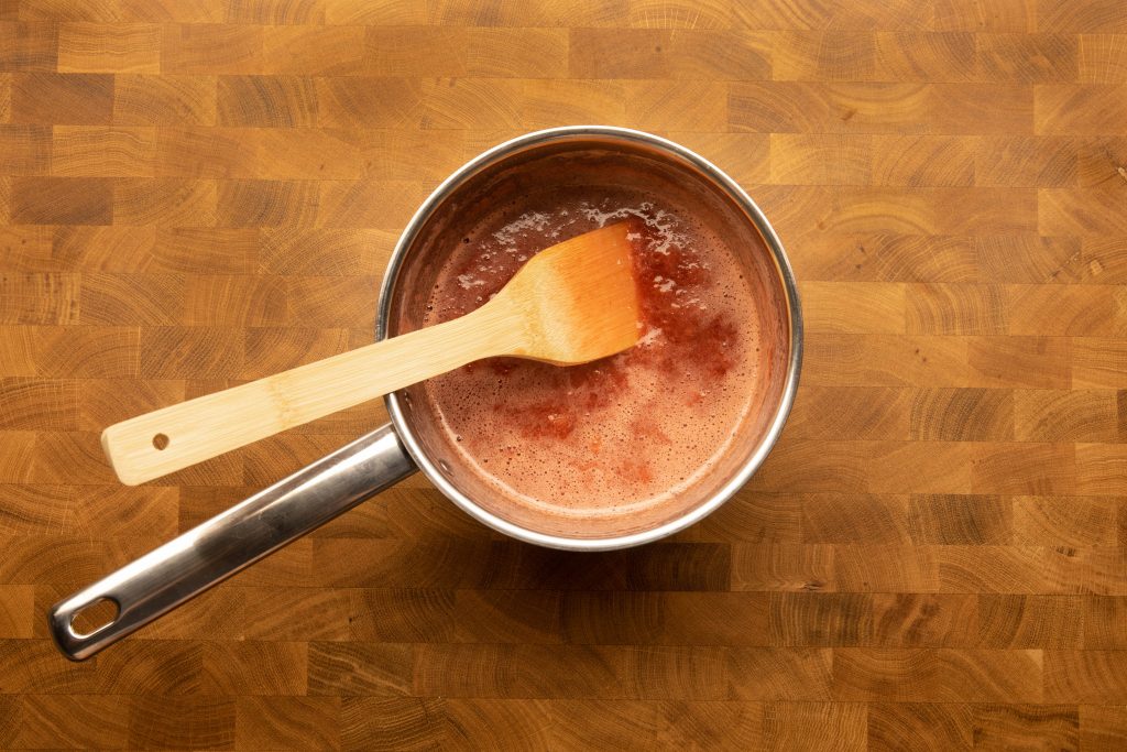 boiling strawberry jam in the pot with spatula