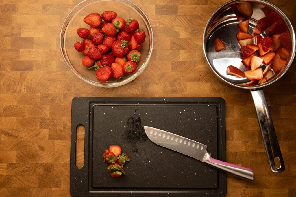 Sugar free strawberry jam cutting strawberries into quarters for jam