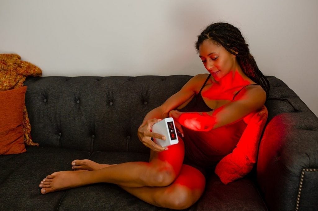 woman using red light therapy device