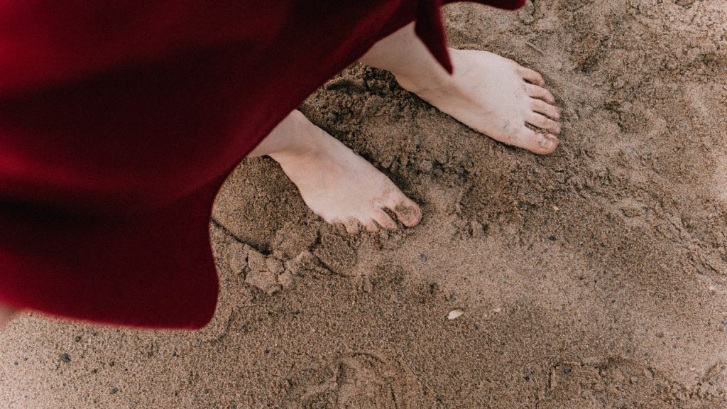woman walking barefoot on sand