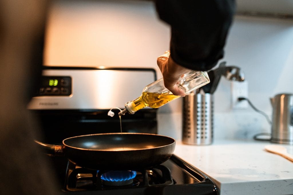 man using cooking oil to season cast iron